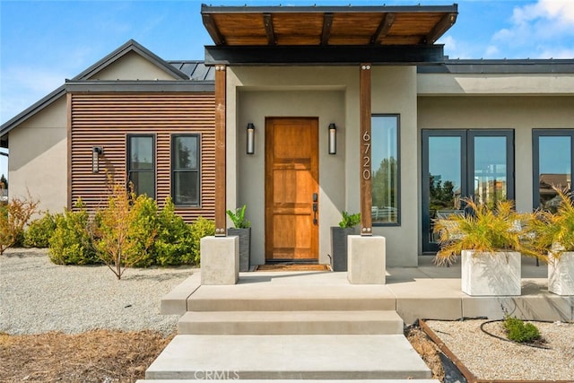entrance to property featuring a standing seam roof, stucco siding, and metal roof