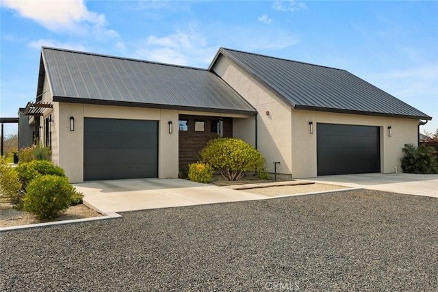 view of front of home featuring metal roof, stucco siding, an attached garage, and concrete driveway