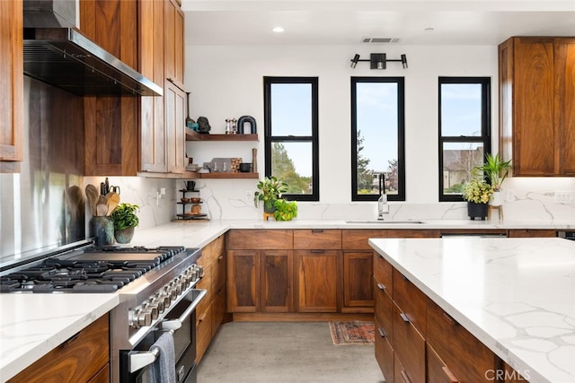 kitchen with brown cabinetry, exhaust hood, a sink, and stainless steel range