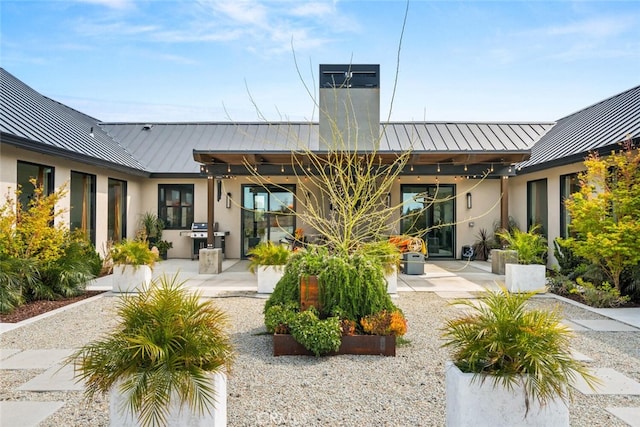 back of property featuring a patio, metal roof, a standing seam roof, and stucco siding