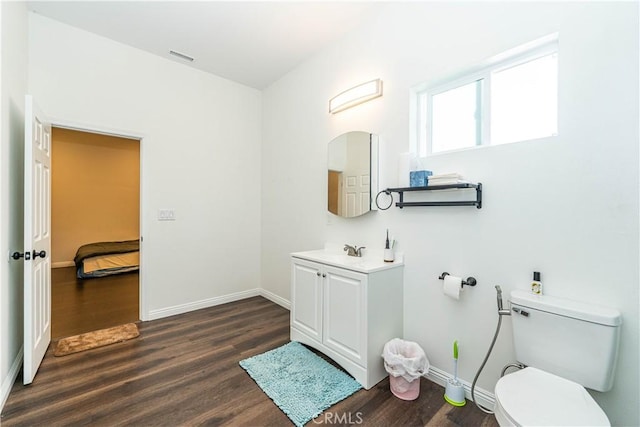 bathroom with toilet, vanity, baseboards, and wood finished floors