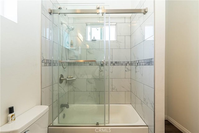 full bathroom featuring toilet, enclosed tub / shower combo, and baseboards