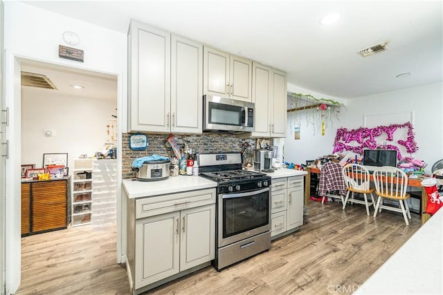 kitchen featuring light wood finished floors, backsplash, light countertops, and appliances with stainless steel finishes