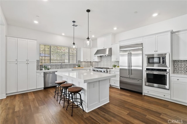 1711 Sonora Creek Ln, Lake Forest, CA 92610 - kitchen featuring built in appliances, dark wood-style floors, light countertops, under cabinet range hood, and a kitchen bar