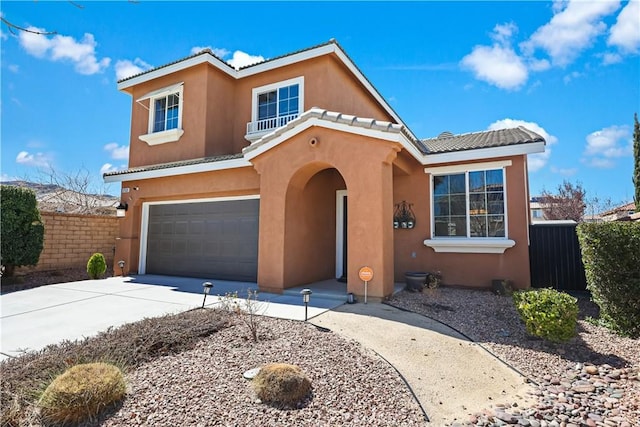 mediterranean / spanish-style house featuring fence, a tiled roof, concrete driveway, stucco siding, and a garage