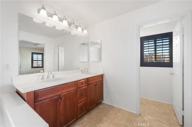 full bath featuring double vanity, tile patterned floors, baseboards, and a sink