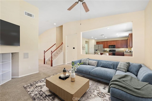 living room with visible vents, baseboards, ceiling fan, light colored carpet, and stairs