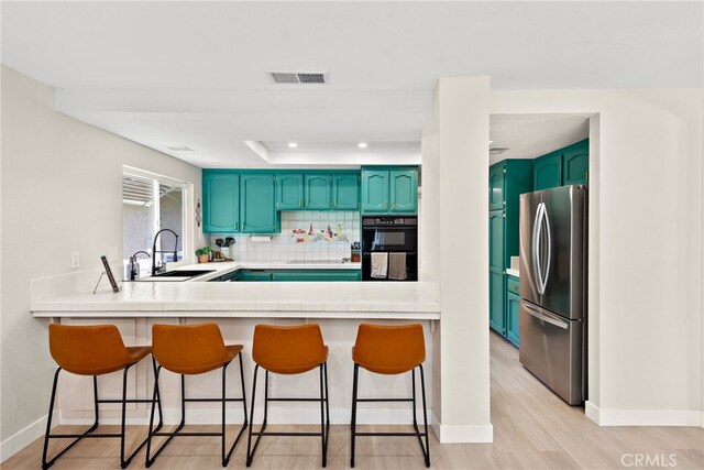 5649 Roane Dr, Oceanside, CA 92057 - kitchen with freestanding refrigerator, a sink, a peninsula, backsplash, and a breakfast bar
