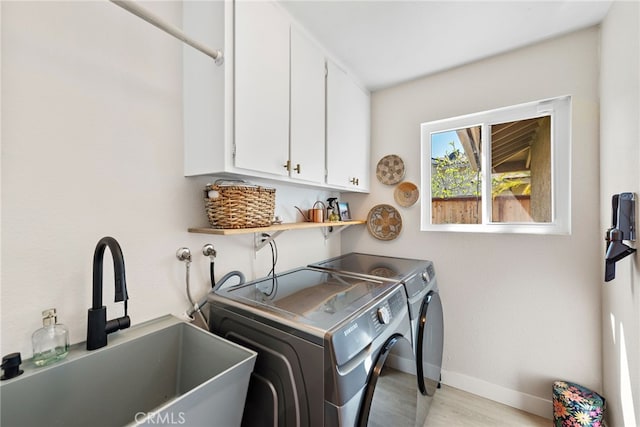 5649 Roane Dr, Oceanside, CA 92057 - laundry area featuring independent washer and dryer, baseboards, light wood-type flooring, and cabinet space