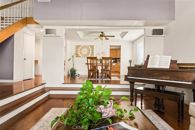 interior space featuring a ceiling fan, stairs, wood finished floors, a raised ceiling, and baseboards