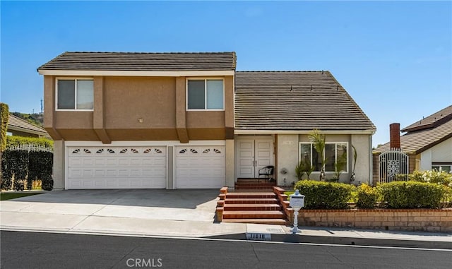view of front of home with an attached garage, concrete driveway, a tiled roof, and stucco siding