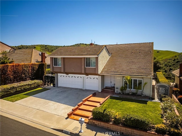 traditional home with a front lawn, driveway, a tiled roof, a garage, and stucco siding