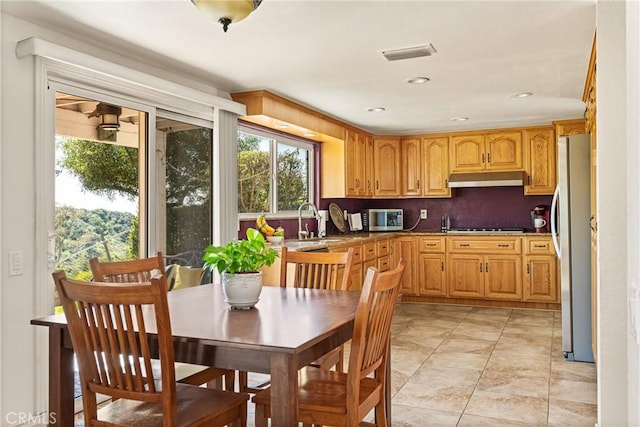 kitchen featuring under cabinet range hood, visible vents, a sink, decorative backsplash, and appliances with stainless steel finishes