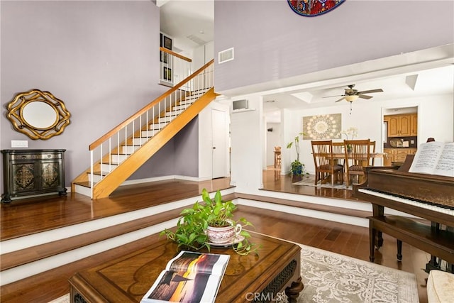 living room featuring visible vents, a ceiling fan, wood finished floors, and stairway