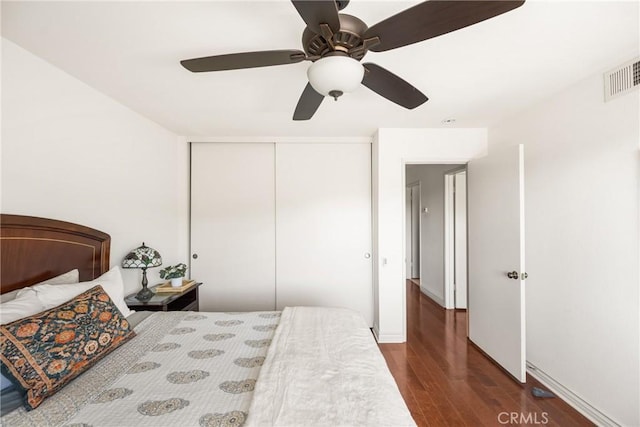 bedroom with baseboards, visible vents, a ceiling fan, wood finished floors, and a closet