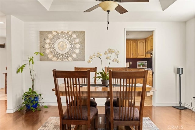 dining space featuring wood finished floors, a ceiling fan, and baseboards
