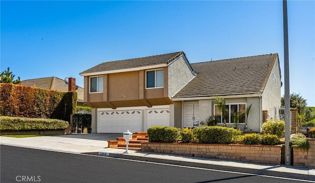 traditional-style house featuring stucco siding, an attached garage, driveway, and a tiled roof