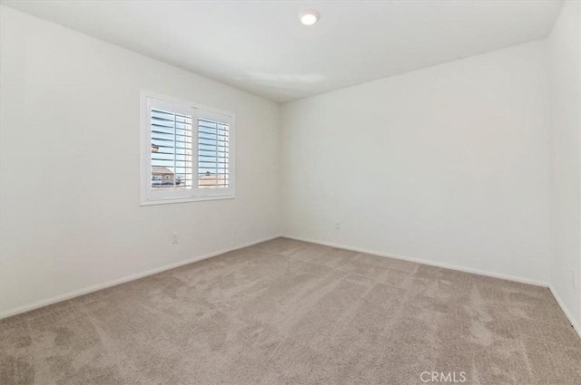 empty room with light colored carpet and baseboards