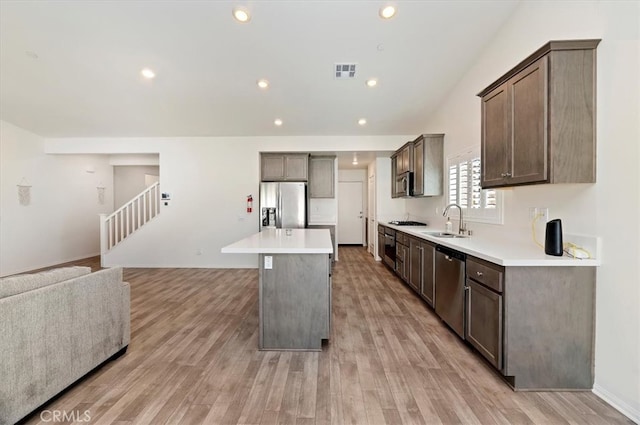 kitchen featuring visible vents, dark brown cabinetry, light wood-style flooring, appliances with stainless steel finishes, and a sink