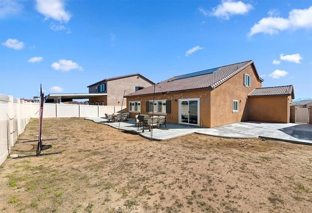 back of house with a patio area, a tiled roof, a fenced backyard, and stucco siding