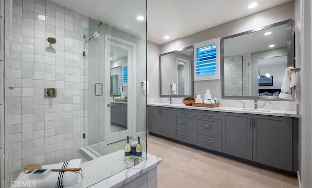 bathroom with double vanity, recessed lighting, a stall shower, and a sink
