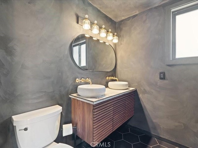 bathroom with tile patterned floors, toilet, double vanity, and a sink