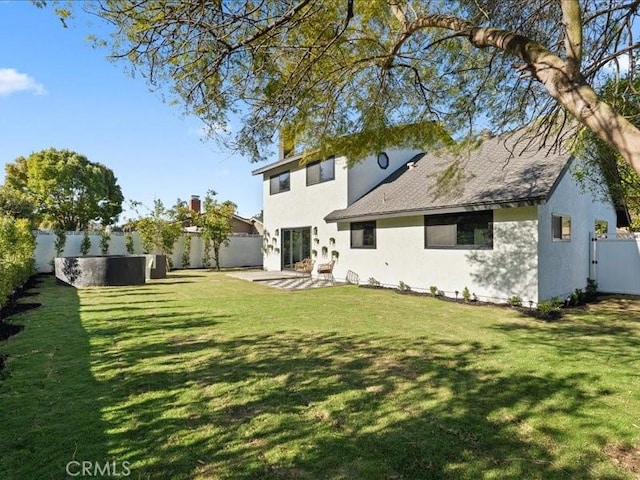 rear view of property featuring a yard, a patio, a fenced backyard, and stucco siding