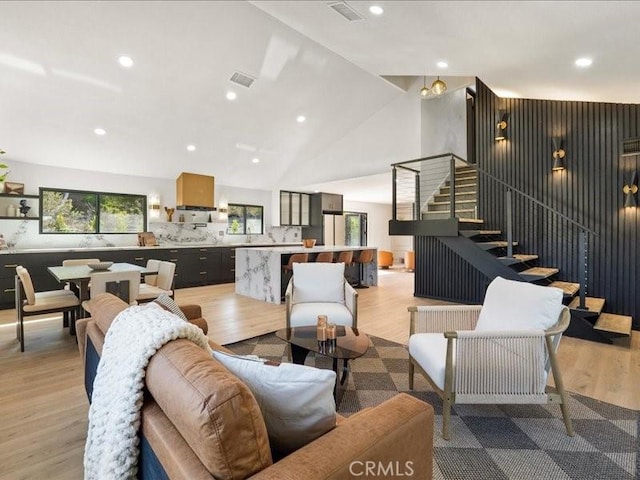 living room with visible vents, stairs, and light wood finished floors
