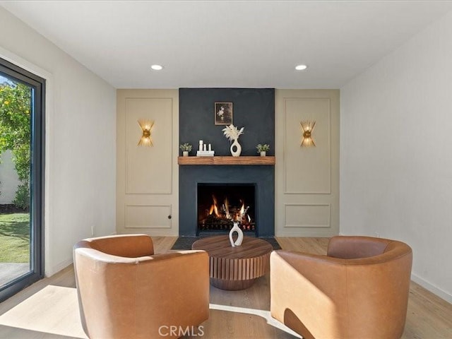 living area featuring recessed lighting, baseboards, wood finished floors, and a fireplace