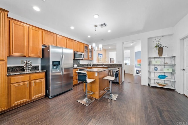 13325 Via Constanza Unit 2, San Diego, CA 92129 - kitchen featuring stainless steel appliances, a kitchen bar, glass insert cabinets, brown cabinetry, and dark wood-type flooring