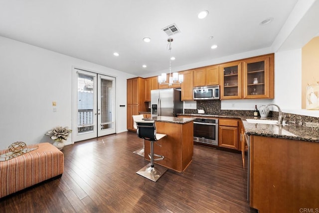 13325 Via Constanza Unit 2, San Diego, CA 92129 - kitchen with appliances with stainless steel finishes, a kitchen breakfast bar, glass insert cabinets, brown cabinets, and recessed lighting