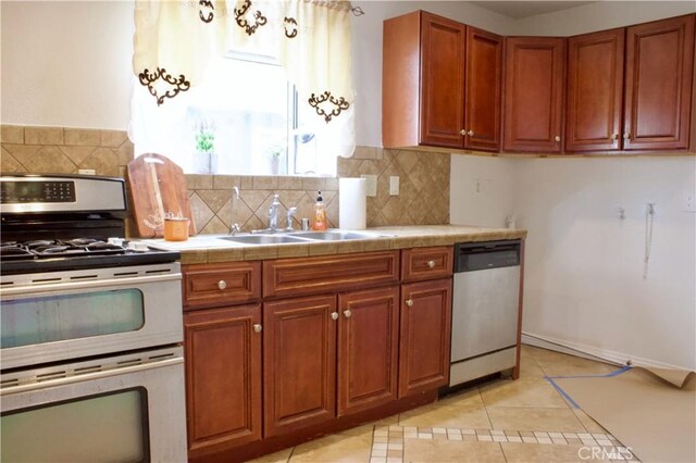323 E Hanna St, Colton, CA 92324 - kitchen featuring light tile patterned floors, brown cabinets, a sink, stainless steel appliances, and tasteful backsplash