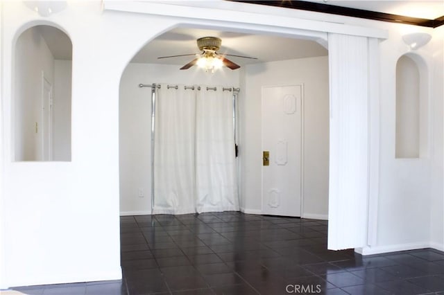 323 E Hanna St, Colton, CA 92324 - spare room with dark tile patterned floors, arched walkways, a ceiling fan, and baseboards