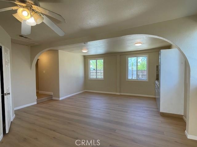 9286 San Benito Ave, Gerber, CA 96035 - unfurnished room with wood finished floors, visible vents, baseboards, arched walkways, and ceiling fan