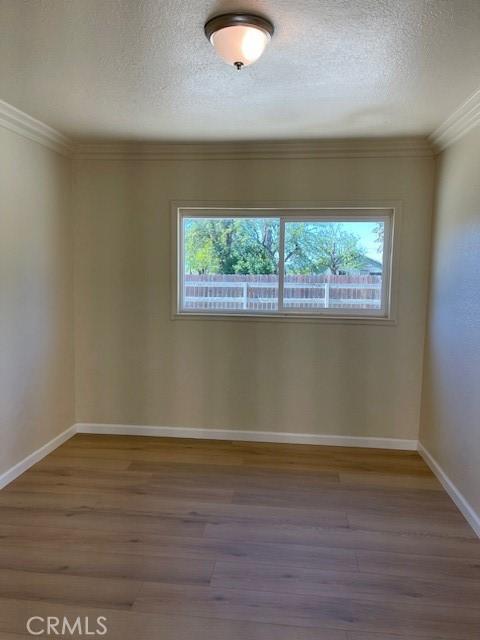 9286 San Benito Ave, Gerber, CA 96035 - unfurnished room with a textured ceiling, crown molding, baseboards, and wood finished floors