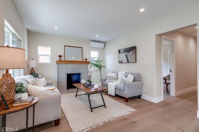 living area with recessed lighting, baseboards, light wood-type flooring, and a wall unit AC