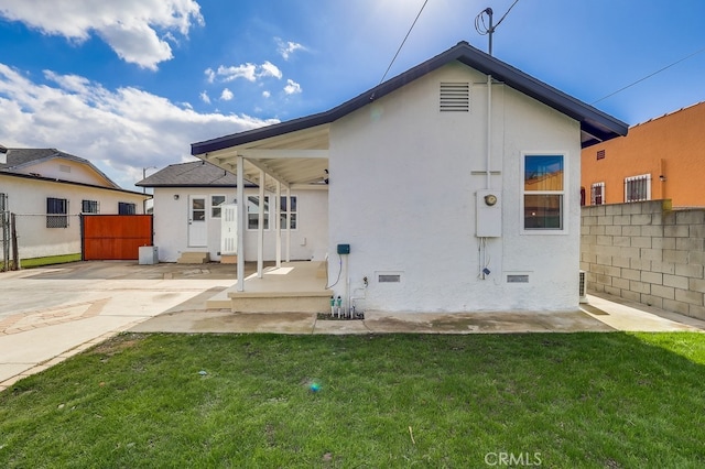 back of house with fence, a yard, stucco siding, entry steps, and a patio area