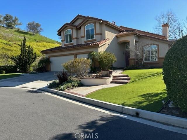 mediterranean / spanish-style home with a chimney, a garage, stucco siding, and concrete driveway