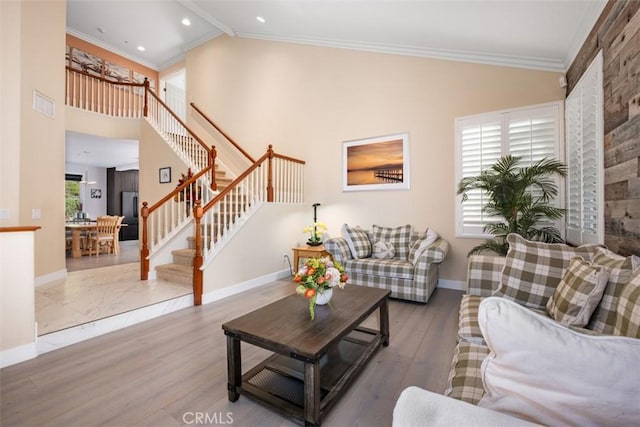 living room featuring ornamental molding, visible vents, lofted ceiling, stairs, and baseboards