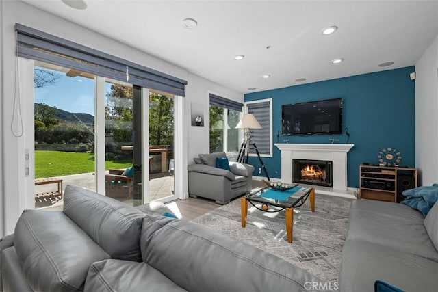 living room featuring recessed lighting, wood finished floors, and a lit fireplace