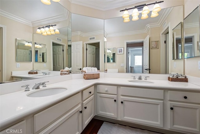 full bath with a sink, visible vents, double vanity, and crown molding