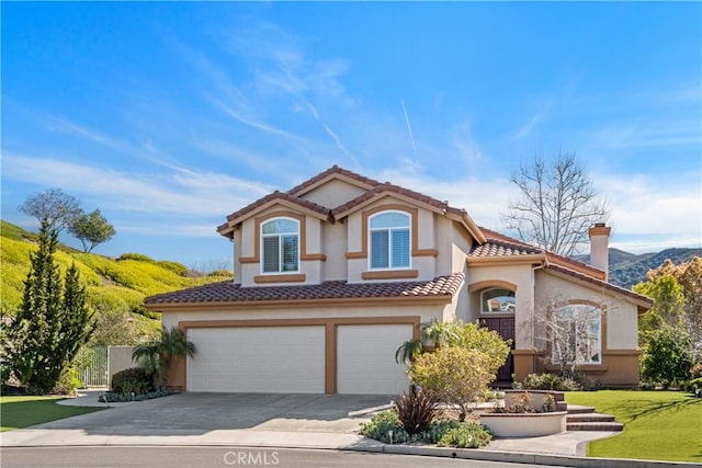 mediterranean / spanish house with stucco siding, driveway, a front lawn, a garage, and a tiled roof