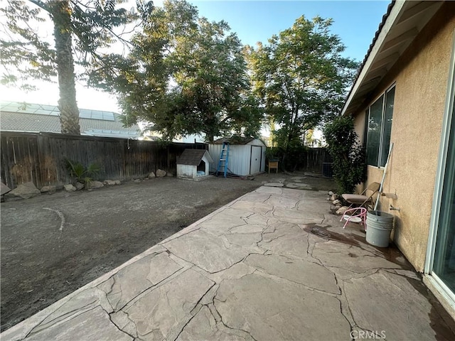 view of patio / terrace featuring a fenced backyard, an outdoor structure, and a shed