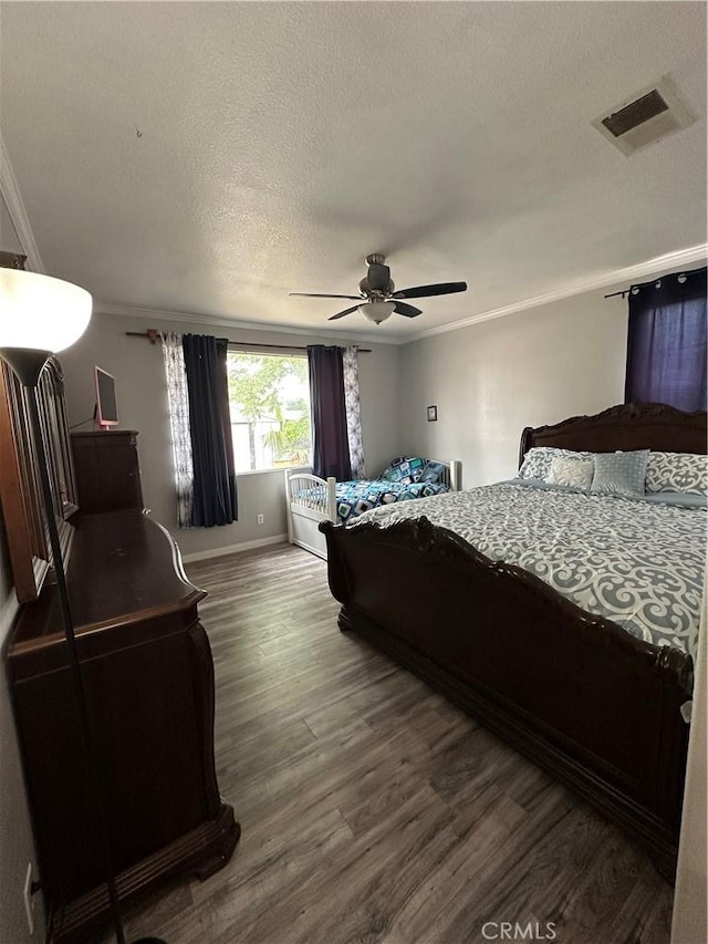 bedroom featuring crown molding, a ceiling fan, visible vents, and wood finished floors