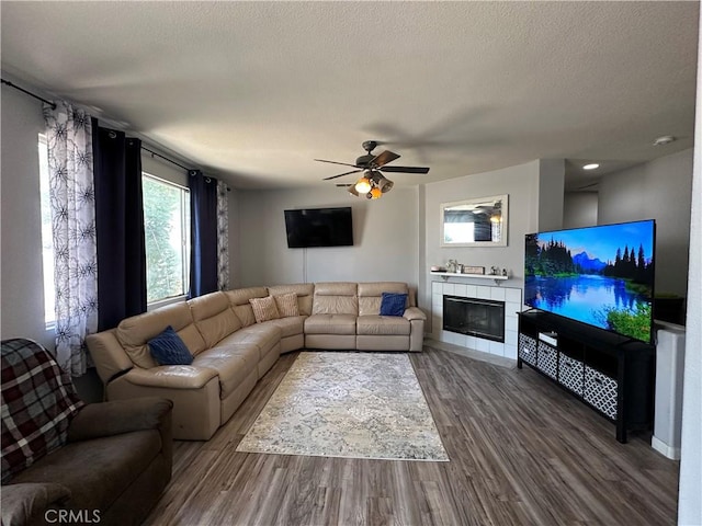 living room with a textured ceiling, ceiling fan, wood finished floors, and a fireplace