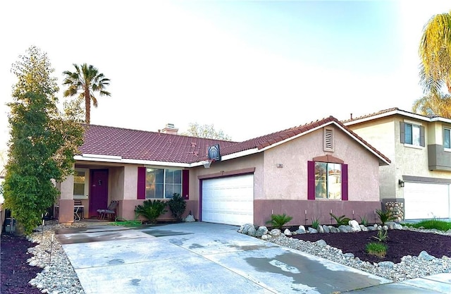 view of front of home featuring stucco siding, a chimney, a tiled roof, concrete driveway, and an attached garage