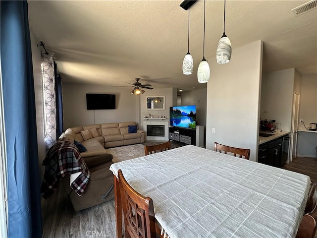 bedroom with a glass covered fireplace, wood finished floors, and visible vents