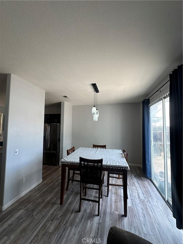 dining area featuring baseboards, a textured ceiling, and wood finished floors