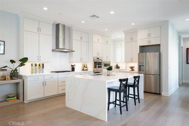 135 Bosal, Irvine, CA 92618 - kitchen with stainless steel refrigerator with ice dispenser, wall chimney range hood, black cooktop, light wood-style flooring, and recessed lighting