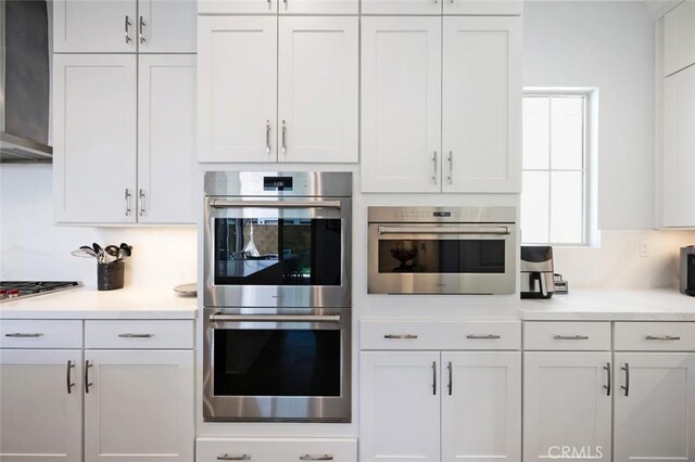 135 Bosal, Irvine, CA 92618 - kitchen featuring appliances with stainless steel finishes, wall chimney range hood, light countertops, and white cabinetry